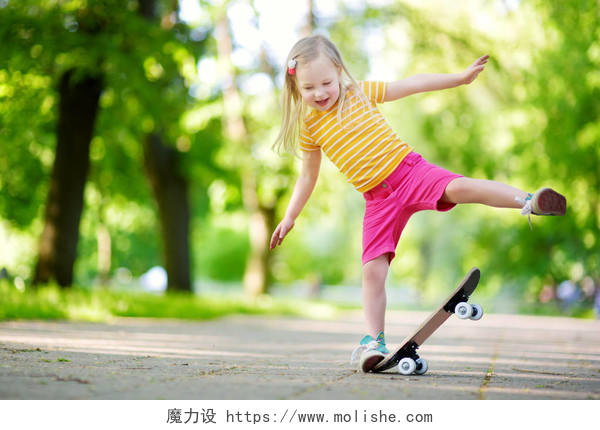夏天在公园里玩滑板的漂亮的小女孩微笑的小女孩